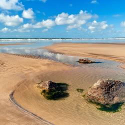 An image of the beach and rock pool at Westward Ho on a bright sunny day